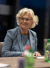 Ministerin Lambrecht sitzt an einem Tisch und lächelt