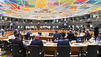 Der Saal für das Ministertreffen, verschiedene Personen sind sitzend von hinten zu sehen.