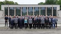 Soldaten und Zivilisten stehen für ein Gruppenfoto vor einem Gebäude.