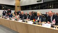 Ministerin Lambrecht sitzt mit Verteidigungsministern verschiedener Nationen an einem langen Tisch.