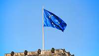 Die Europaflagge weht im Wind vor hellblauem Himmel.