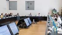Mehrere Personen sitzen an einem Konferenztisch in einem Saal