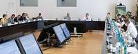 Mehrere Personen sitzen an einem Konferenztisch in einem Saal