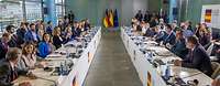 Ministerin Lambrecht sitzt mit deutschen und spanischen Politikern, sowie Kanzler Scholz an zwei Tischen und unterhalten sich.