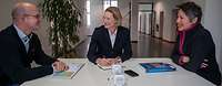 Frau Staffa sitzt an einem Tisch zwischen zwei weiteren Personen und unterhält sich.