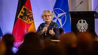 Verteidigungsministerin Christine Lambrecht sitzt in einem Stuhl auf einer Bühne und spricht.