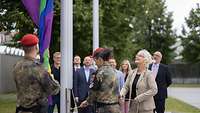 Zwei Soldaten und Verteidigungsministerin Lambrecht hissen die Regenbogenflagge.