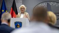 Verteidigungsministerin Christine Lambrecht steht hinter einem Pult und spricht.