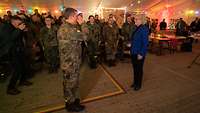 In einem Festtagszelt salutiert ein deutscher Soldat Christine Lambrecht, im Hintergrund sind weitere Soldaten.