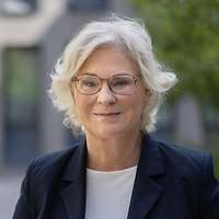 Ein Porträt von Ministerin Lambrecht, die in einem sonnigen Hof steht.