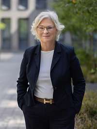 Ein Porträt von Ministerin Lambrecht, die in einem sonnigen Hof steht.