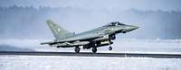 Ein Kampfflugzeuge vom Typ Eurofighter startet, im Hinter- und Vordergrund liegt Schnee.