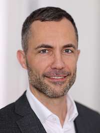 Der Pressesprecher des BMVG, Michael Stempfle, schaut in die Kamera für eine Portraitaufnahme.