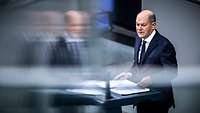 Bundeskanzler Olaf Scholz spricht im Bundestag an einem Rednerpult.