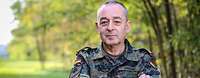 Thie Chief of Defence Carsten Breuer is standing infront of woodland and looking directly into the camera.