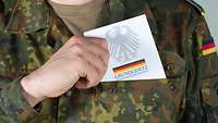 Ein Soldat steckt das 'Grundgesetzt' in seine Brusttasche seiner Uniform