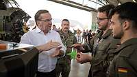 Boris Pistorius is talking to two servicemen in an aircraft hangar