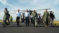 The NATO Secretary General, the German Defence Minister and the Chief of the German Army are walking across an airfield