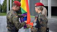 Zwei Soldaten bereiten das Hissen der Regenbogenflagge vor.