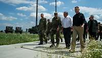 Deutsche Soldaten, Boris Pistorius und Mariusz Blaszczak laufen an Geräten der Bundeswehr vorbei.