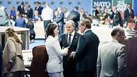 Annalena Baerbock, Olaf Scholz und Boris Pistorius unterhalten sich in einem großen Konferenzsaal.