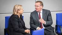Eva Högl und Boris Pistorius sitzen im Bundestag und unterhalten sich miteinander.