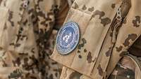 Auf dem Feldanzug eines deutschen Soldaten haftet der blaue Patch der United Nations.