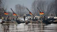 Deutsche Soldaten fahren mit einer Schwimmschnellbrücke Amphibie M3 über einen Fluss.