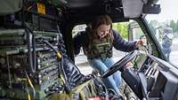 Eine junge Frau mit einer Tarnweste steigt in ein militärisches Fahrzeug.