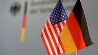 Eine deutsche und eine US-amerikanische Flagge stehen auf dem Tisch