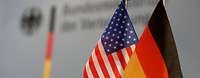 Eine deutsche und eine US-amerikanische Flagge stehen auf dem Tisch