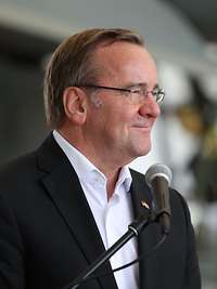 Boris Pistorius steht vor einem Mikrofon und lächelt.