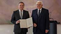 Boris Pistorius hält Urkunde neben Frank Walter Steinmeier vor Rednerpult