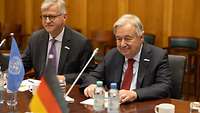 António Guterres sitzt mit seiner Delegation an einem Tisch und unterhält sich mit Personen außerhalb des Bildes.
