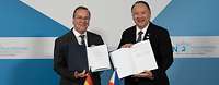 Boris Pistorius und Gilberto C. Teodoro stehen nebeneinander und halten unterzeichnete Dokumente zum Betrachter.