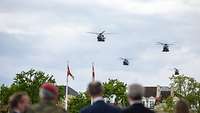 Drei Hubschrauber fliegen über Zuschauer