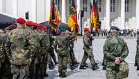 At a military ceremony german soldiers walk in a formation across a square.