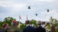 Three military helicopters fly by the Audience, they can be seen blurry in the foreground.