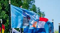 Die Flagge des NATO-Gipfels 2025 weht mit anderen Fahnen im Wind.