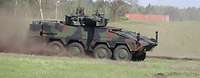 Ein Radpanzer fährt im Gelände und wirbelt Staub auf