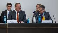 Boris Pistorius sitzt neben einem Mann an einem Konferenztisch und lächelt