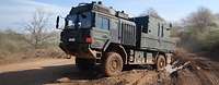 Ein Transportfahrzeug der Bundeswehr fährt, schräg zum Betrachter auf, offenem Gelände.