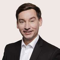 Sebastian Hartmann schaut für eine Portraitaufnahme freundlich in die Kamera.