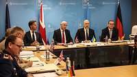 Mark Rutte, John Healey, Denis Shmyhal und Boris Pistorius sitzen nebeneinander. Dahinter die entsprechenden Flaggen.