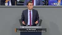 Ein Mann in blauem Anzug steht an einem Rednerpult am Bundestag
