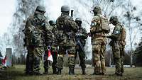 Mehrere Soldaten stehen sich in einem Kreis gegenüber und sprechen miteinander.