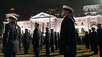 Rekrutinnen und Rekruten stehen bei Dunkelheit vor dem beleuchteten Reichstag.