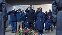 Mehrere Personen zivil und in Uniform salutieren vor einem Kranz im Ehrenmal der Bundeswehr