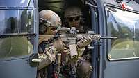 Ein Soldat sitzt mit dem Gewehr G95 im Anschlag im Hubschrauber