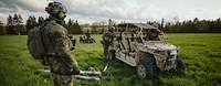 Auf offenem Gelände stehen Fahrzeuge der Bundeswehr und Soldaten.